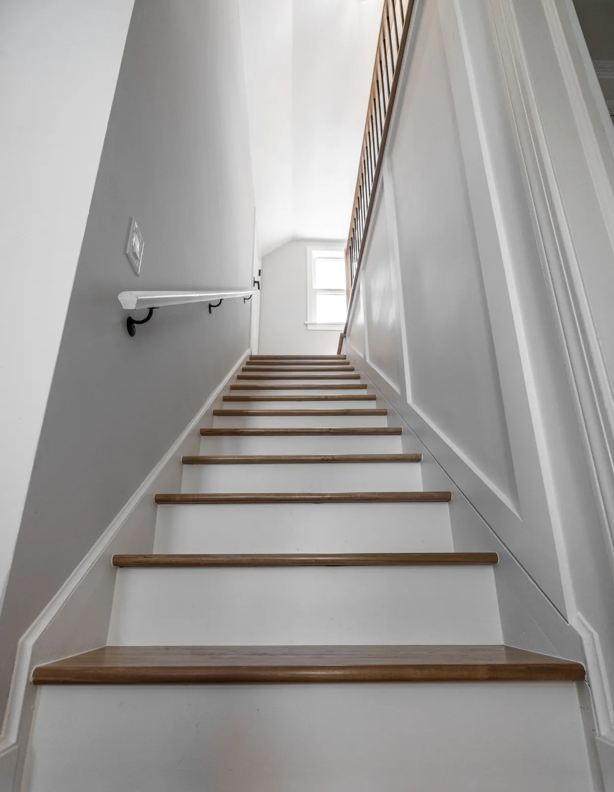 Full staircase view looking up with wall-mounted handrail